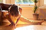 Graceful woman practicing yoga side lunge in sunny window