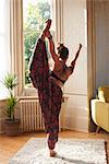 Graceful woman practicing yoga king dancer pose in apartment