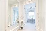 White, luxury home showcase interior corridor with mirror