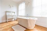 White, luxury home showcase interior bathroom with soaking tub and parquet hardwood floor