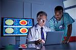 Male surgeon and doctor working at laptop in hospital conference room