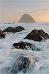 Seascape with breaking waves over rocks at dusk.