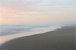 Landscape with sandy beach and ocean at sunset.