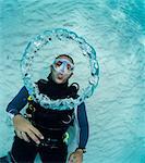 Scuba diver blowing bubble rings.  As the escaping air rises to surface, the decrease in pressure causes the rings of air to expand.