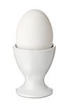 Whole white egg in a ceramic eggcup, isolated on white background. Breakfast food.