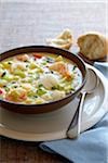 Bowl of seafood chowder soup with a spoon and crusty bread