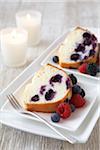 Vanilla bundt cake with mixed berries on white plate with a fork