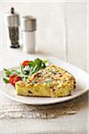 Ham and spincah frittata with simple salad on a white plate