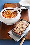 Ham hock soup served with multigrain bread on a wooden cuttting board with blue linen tablecloth