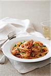 Shrimp linguine on a white plate with linen napkin and a glass of white wine