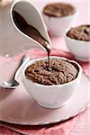 Individual chocolate souffle with chocolate sauce poured on top on a pink background