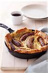 Baked sausage and pancake breakfast in cast iron skillet with a cup of coffee