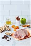 Pork chop dinner ingredients on a marble countertop with white tiled kitchen backsplash