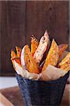 Roasted sweet potato wedges with sea salt and pepper in a black basket with parchment paper