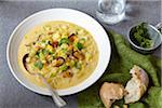 Bowl of seafood chowder with crusty bread on a grey table with a green napkin