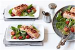 Salmon fillets with spinach and tomato salad on dinner plates