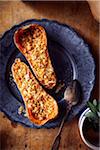 Stuffed butternut squash baked with cheese and sage on a blue dinner plate