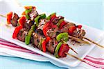 Grilled steak and pepper skewers on a platter with red striped napkin