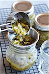 Scooping tomatillo salsa into canning jars