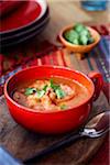 Tomato and shrimp soup in a red bowl topped with cilantro