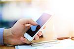 Close up of a man using mobile smart phone in modern office