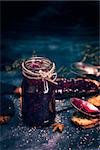 Raspberry jam in a glass jar and pieces of fried bread on a black background