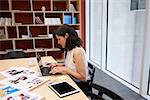 Woman in creative media office using laptop, horizontal
