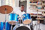 Male Teenage Pupil Playing Drums In Music Lesson