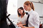 Female Pupil With Teacher Playing Piano In Music Lesson