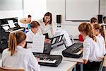 Teenage Students Studying Electronic Keyboard In Music Class