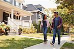 Couple Walking Along Suburban Street Holding Hands