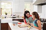 Jewish girl glazing plaited challah bread dough with her mum