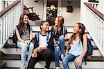 Young teen girls on front steps of house with school bags