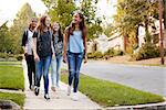 Four young teen girls walking to school together, front view