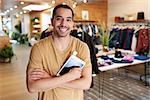 Man with tablet computer smiling to camera in a clothes shop