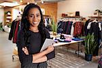 Young woman with tablet smiling to camera in a clothes shop