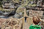 Over shoulder view of boy, brother and mother crossing Inca rope bridge, Huinchiri, Cusco, Peru