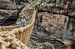 Female tourist looking out from Inca rope bridge, Huinchiri, Cusco, Peru