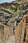 Mature woman crossing Inca rope bridge, Huinchiri, Cusco, Peru