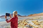 Woman photographing landscape, using digital tablet, Salar de Chalviri, Chalviri, Oruro, Bolivia, South America