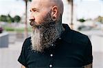 Portrait of mature male hipster with grey beard and earring plug, head and shoulders