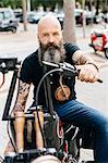 Portrait of mature male hipster astride motorcycle in parking lot