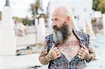 Mature male hipster revealing tattooed chest