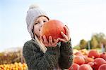 Girl holding harvested pumpkin in field