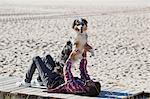 Man lying on beach boardwalk playing with dog