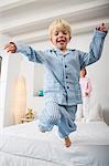 Boy and female twin jumping from bed
