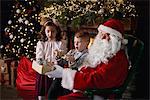 Young girl and boy visiting Santa, receiving gifts