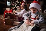 Young girl and boy sorting Christmas gifts, young boy rolling list