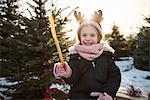 Girl in christmas tree forest wearing antlers, portrait