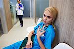 Surgeon sitting in hospital hallway, holding glass of water, pensive expression